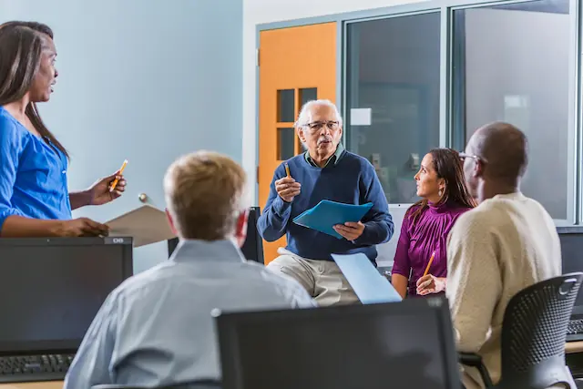 Een ervaren opleider die instructies geeft aan een groep professionals in een trainingsruimte, symbool voor de functie als praktijkopleider van bedrijfsarts Van Bennekom